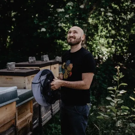 Peter Markl bei den Bienenstöcken, den Schleier in der Hand